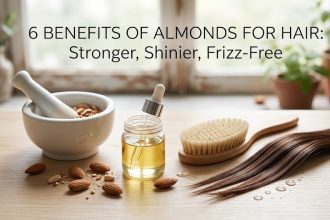 A wooden bowl filled with fresh almonds next to a bottle of almond hair oil, symbolizing natural hair care.