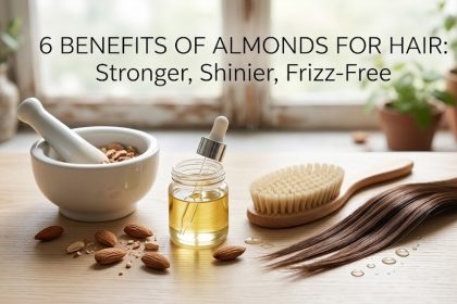 A wooden bowl filled with fresh almonds next to a bottle of almond hair oil, symbolizing natural hair care.